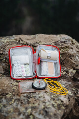 Tablets for pain, an elastic bandage in a roll, a compass on a rope, a red first-aid kit, a set of...