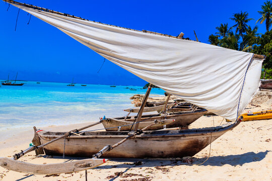 Traditional wooden dhow boats ashore on tropical sandy Nungwi beach in the Indian ocean on Zanzibar, Tanzania