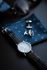 Business accessories. Mens watch and cufflinks isolated on black background.