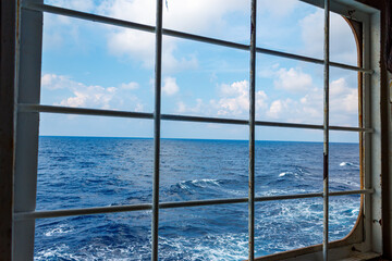 Ship's open side hatch fortified with crossing metal bars. Anti piracy protection. HRA, High Risk Areas. Illegal boarding. Ocean background.