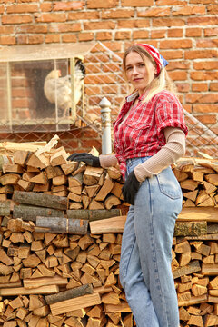 young woman in work clothes on the background of firewood and a brick wall
