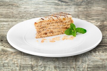 Tasty sweet cake decorated with fresh green mint leaf on white ceramic plate.Traditional dessert.