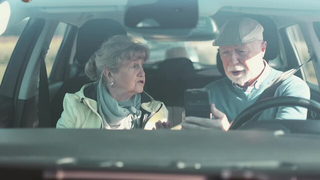 Senior couple using gps on their mobile phone during a road trip
