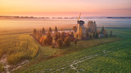 Traditional Wooden Windmill Morning Landscape. Rural colorful Sunrise, Foggy green fields. Dudutki village