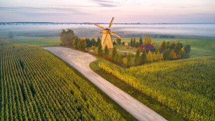 Traditional Wooden Windmill Morning Landscape. Rural colorful Sunrise, Foggy green fields. Dudutki village
