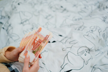 women's hands count a stack of money of a banknotes of 5000 rubles in bed 