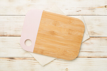 Cutting board with towel on wooden background, top view