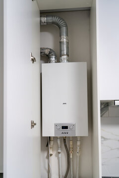 Opened Kitchen Cabinet And LPG Gas Boiler Inside Furniture. Gas Central Heating Condensing Boiler Fitted Inside Cabinet.