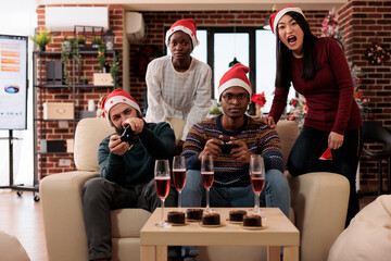 Festive coworkers playing online video games to celebrate christmas eve at office party with...