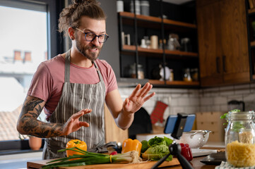 Young smiling male hipster healthy food blogger preparing a meal or his web audience