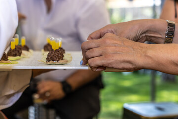 close up of a hand picking up a canapé from a catering table carried by a waiter at a gourmet food event. modern gastronomy