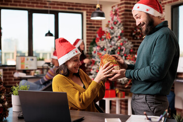 Male worker giving present box to woman in office, celebrating christmas eve holiday with gifts....