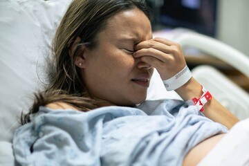Sick depressed patient laying in bed in the hospital. Health problems and miscarriage.