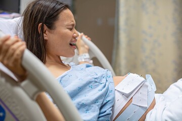 A woman having labor contractions in the hospital, screaming in pain. Childbirth.