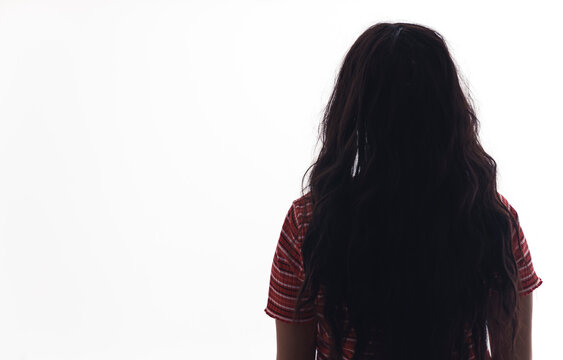 Rear view of unrecognisable young woman with long dark hair back turned to camera facing away. Isolated white background. Horizontal studio shot. High quality photo