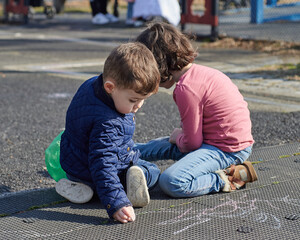 siblings drawing in chalk at the playground
