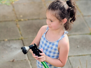 beautiful girl in a bathing suit is watering plants on a summer day