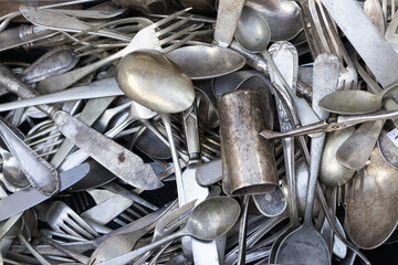 closeup of several old silver cutlery pilled up. antiques and second hand market