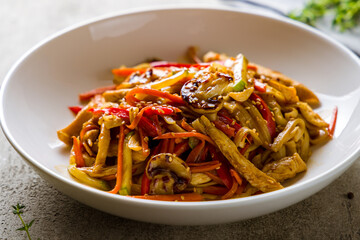 chicken wok noodles with vegetables on grey table macro close up