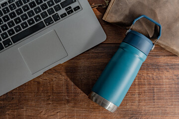 a thermos lying on a wooden table at an office.