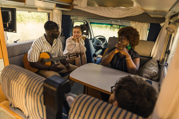 Millennial travelers inside their camper. Multi-ethnical group of friends enjoying afternoon by...