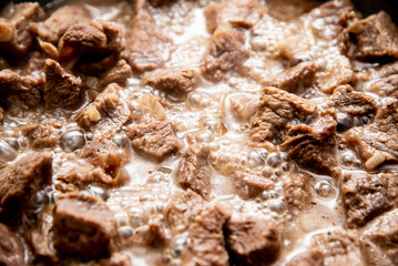 close-up beautiful large pieces of fried meat with onions in a pan
