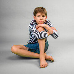 Young boy in striped shirt sitting casually on floor with his chin on his knee © 3Days2Go Media