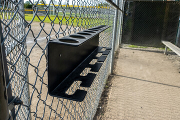 Close up view of a baseball bat holder inside a dugout at a sports field park - obrazy, fototapety, plakaty
