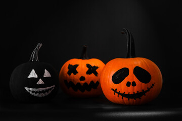 Halloween celebration. Pumpkins with drawn faces on table in darkness