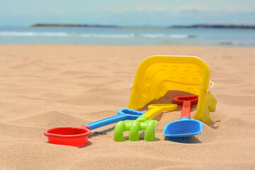 Set of colorful beach toys on sand near sea