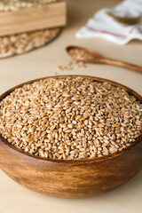 Bowl of wheat grains on white wooden table, closeup