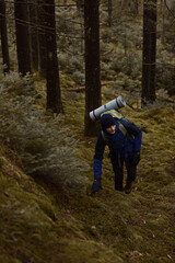 A caucasian male hiker with a backpack hiking in a pine forest.