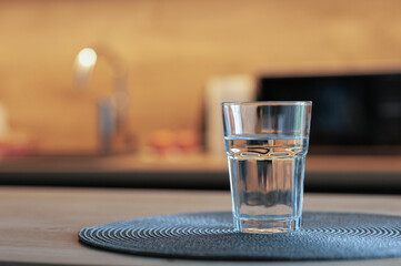 Glass of water on wooden table in kitchen. Space for text