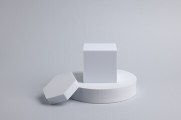 Scene with podium for product presentation. Figures of different geometric shapes on light grey...