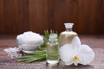 Fototapeta na wymiar Essential oils, orchid flower and sea salt on wooden table, closeup