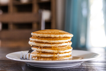 A plate with a stack of homemade pancakes at a dark wood kitchen dining room table
