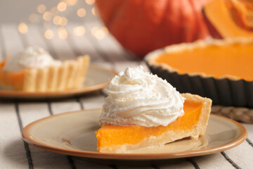 Piece of fresh homemade pumpkin pie with whipped cream on table