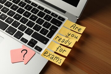 Laptop with phrase Are You Ready For Exams? made of post note stickers on wooden table