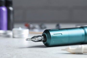 Modern professional tattoo machine on white table, closeup