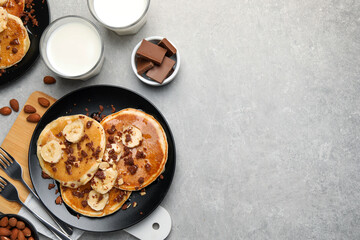 Tasty pancakes with sliced banana served on light grey table, flat lay. Space for text