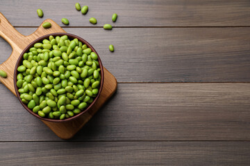 Bowl of delicious edamame beans on wooden table, flat lay. Space for text