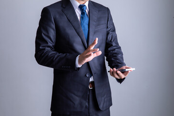 携帯電話を操作するスーツを着た男性　Business