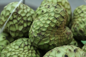 Delicious green cherimoya fruits on market stall, closeup