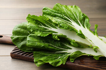 Leaves of fresh green pak choy cabbage with water drops on wooden table, closeup - obrazy, fototapety, plakaty