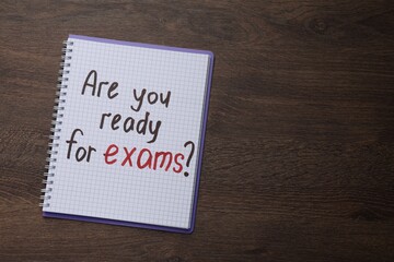 Notebook with question Are You Ready For Exams? on wooden table, top view. Space for text