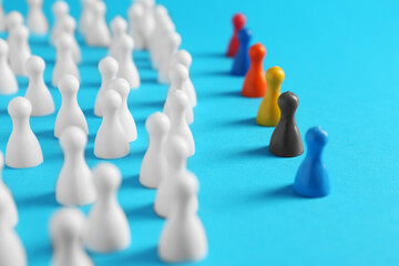 Colorful pawns on light blue background, closeup. Social inclusion concept