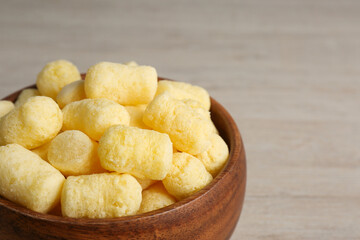 Bowl of corn sticks on wooden table, closeup. Space for text