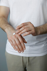 Man applying cream onto hand against grey background, closeup