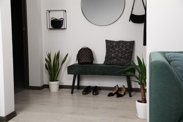 Stylish bench, shoes and backpack near light wall in hallway