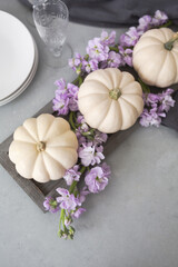 Fototapeta na wymiar Three White Ghost Pumpkins on a Gray Tray with Purple Stock Flowers